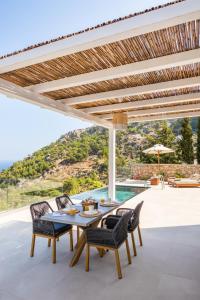 a patio with a table and chairs and a pool at MerTelia Luxury Villas in Kyra Panagia