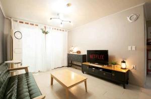 sala de estar con sofá y TV en Ria House en Goyang