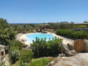 a swimming pool in a yard with trees and rocks at Cuccuru Relax - B IUN Q9882 in Orosei