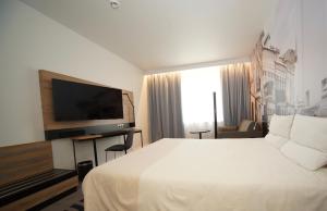 a hotel room with a bed and a flat screen tv at Novotel Vilnius Centre in Vilnius