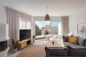 Athenian Riviera Panorama Villa في أثينا: غرفة معيشة مع أريكة وتلفزيون بشاشة مسطحة