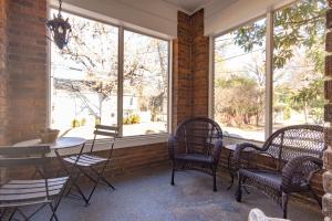 eine Veranda mit Stühlen, einem Tisch und Fenstern in der Unterkunft Classic Central Gardens Flat in Memphis