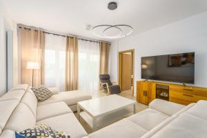 a living room with white furniture and a flat screen tv at Aquamarina Prima SEASIDE Apartments by the Beach by Renters in Międzyzdroje