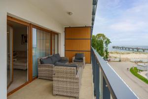 a balcony with wicker furniture and a view of the ocean at Aquamarina Prima SEASIDE Apartments by the Beach by Renters in Międzyzdroje