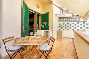 una mesa y sillas en una cocina con persianas verdes en Vintage Apartment with Garden View / Free Parking, en Florencia