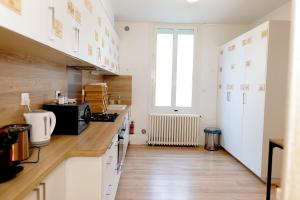 a kitchen with white cabinets and a wooden floor at Grande maison en pierre à Pomerol - 3 chambres, parking, proche Saint-Emilion in Pomerol
