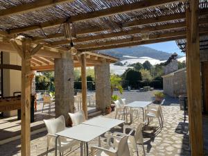 a patio with tables and chairs under a wooden pergola at Kampaoh Fonts d' Algar in Callosa de Ensarriá