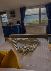 a bed in a room with a view of the ocean at Polhawn Lookout, The Forgotten Chalet in Cawsand