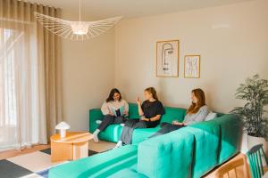 three women sitting on a couch in a living room at Living Lodges - Scandi Lodge in Durbuy