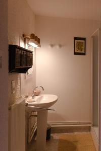 uma casa de banho com um lavatório branco num quarto em Chez Caroline chambres d'hôtes em Bains