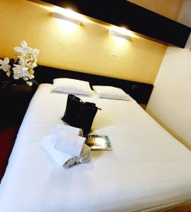 a white bed with two pillows and a book on it at Hôtel du Parc Limoges & Restaurant "Le temps d'une pause" in Limoges