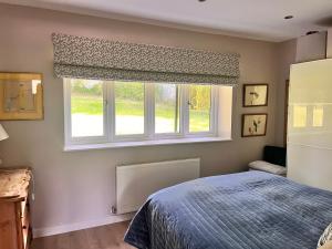 Schlafzimmer mit einem Bett und einem Fenster in der Unterkunft The Coach House in Warnham