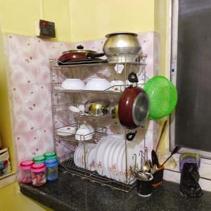 a kitchen rack with dishes and pots and pans at Sweet home in Kolkata