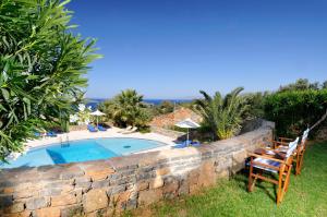 a stone retaining wall with a swimming pool and chairs at Elounda Living Residences by GHH in Elounda