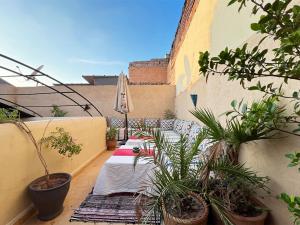 a patio with plants and an umbrella on a balcony at Riad Lazord De Marrakech Entier in Marrakesh