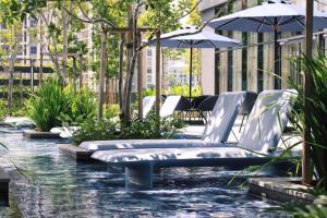 une piscine d'eau avec des chaises et un parasol dans l'établissement Star KLCC By B&B, à Kuala Lumpur