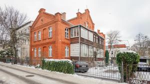 a large red brick building on a snowy street at Apartamenty Sun & Snow Obrońców Westerplatte 8 in Sopot