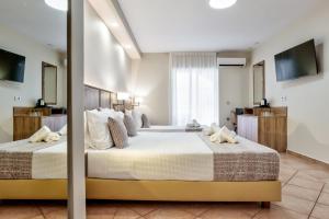 a large bedroom with two beds and a television at White Olive Premium Laganas in Laganas