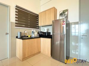 a kitchen with a stainless steel refrigerator and wooden cabinets at Amber Cove Impression City Melaka City Center 8 min to Jonker Street in Melaka