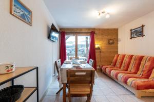 a living room with a couch and a table at Le Chemin des Alpages - Vue montagne in La Giettaz