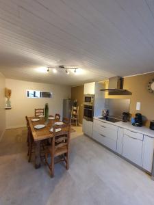 a kitchen with a wooden table and a dining room at La Maison d’Utah in Sainte-Marie-du-Mont