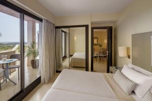 a hotel room with a bed and a balcony at Precise Resort El Rompido-The Club in El Rompido