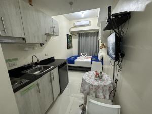 a small kitchen with a table and a bed at Green Residences Stays by PBYY in Manila