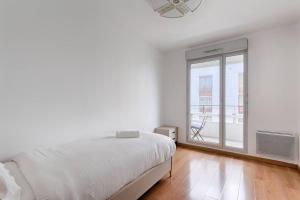 Dormitorio blanco con cama y ventana grande en Saint Denis/Leon Nozal : Magnifique Apartment 5P en Saint-Denis