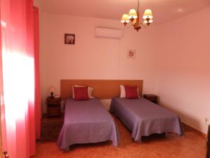 sypialnia z 2 łóżkami i żyrandolem w obiekcie Monte da Vinha Nova w mieście Santiago do Cacém