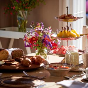 a table topped with plates of food and flowers at Oaklands Farm Stay in Van Reenen