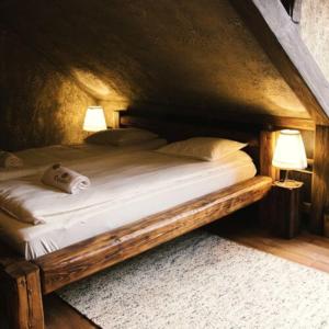 a wooden bed with two lamps in a room at Excalibur Élményfogadó in Eger