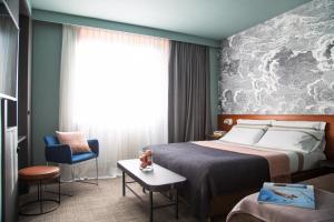 a hotel room with a bed and a chair at Hotel Tremoggia in Chiesa in Valmalenco