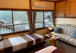 um quarto com uma cama, um sofá e uma janela em Private & Cozy Lodge - basecamp Imari em Imari