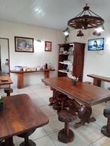 une salle à manger avec des tables et des bancs en bois dans l'établissement Pousada Estância Mineira, à Campo Grande