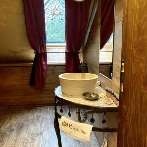 uma casa de banho com uma mesa com um lavatório e uma janela em Excalibur miniHotel em Eger