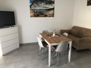 a dining room table with chairs and a couch at Apartmani Gavran in Pirovac
