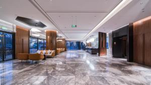 a lobby with chairs and tables in a building at Intercity Hangzhou West Lake Huanglong Hotel in Hangzhou