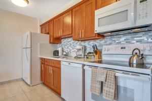 ホノルルにあるGorgeous High Rise Waikiki Condo with Ocean and Diamond Head Viewsのキッチン(白い家電製品、木製キャビネット付)