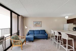 uma sala de estar com um sofá azul e uma cozinha em Waikiki Banyan 28th Floor Ocean View Condo - Free parking & WiFi home em Honolulu
