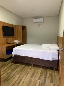 a hotel room with a bed and a flat screen tv at Chalés Vista da Serra in Piumhi