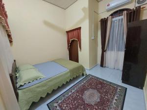 a small bedroom with a bed and a rug at Rumah Teratak Bonda in Jertih