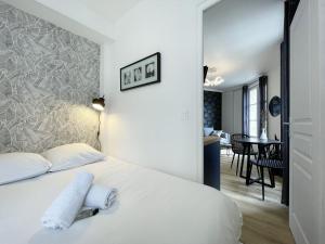 Un dormitorio con una cama blanca y un comedor. en Le Lumineux - Cœur de Ville, en Chartres