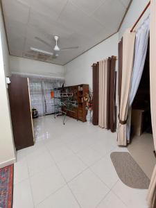 een lege kamer met gordijnen en een kamer met witte tegels bij Rumah Teratak Bonda in Jertih