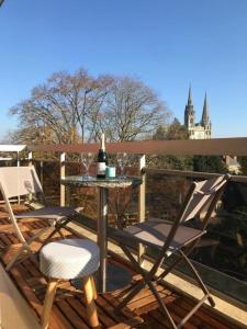 a patio with two chairs and a table with a bottle of wine at Appartement avec parking et balcon vue Cathédrale in Chartres