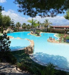 una grande piscina in un resort con persone di Awesome cozy bungalow , pool open from june to september a Gran Alacant