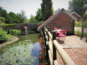 una mesa en una terraza junto a un estanque en Le Lavoir Secret - hébergement atypique dans un joli cadre bucolique, en Dangeau