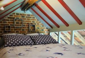 Bett in einem Zimmer mit Ziegelwand in der Unterkunft Le Lavoir Secret - hébergement atypique dans un joli cadre bucolique in Dangeau