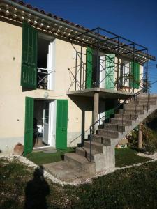 um edifício com portas verdes e escadas em frente em Typique cabanon provençal rénové Attention escalier extérieur pour accéder au 1er étage em Gonfaron