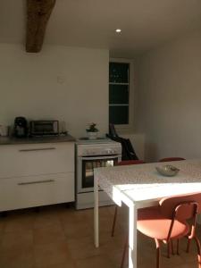uma cozinha com uma mesa, um fogão, uma mesa e cadeiras em Typique cabanon provençal rénové Attention escalier extérieur pour accéder au 1er étage em Gonfaron
