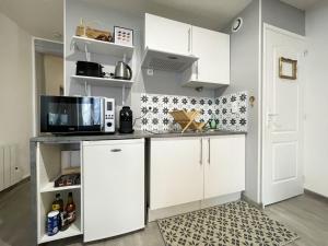 a kitchen with white cabinets and a microwave at The Heart of Chartres in Chartres